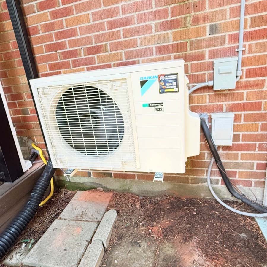 A Daikin cold climate heat pump securely mounted on a metal snow stand to ensure winter clearance beside a Kitchener residence.