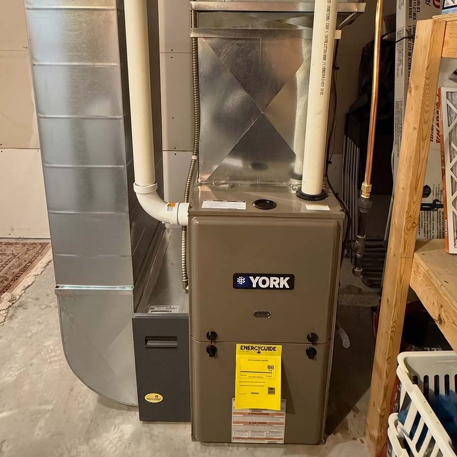 A newly installed high-efficiency gas furnace in a residential basement utility room in Kitchener, showing clean sheet metal ductwork and venting pipes.